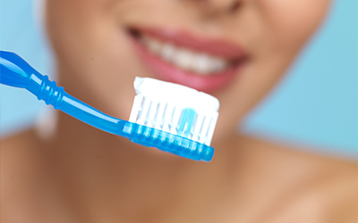 A woman holding a toothbrush and toothpaste